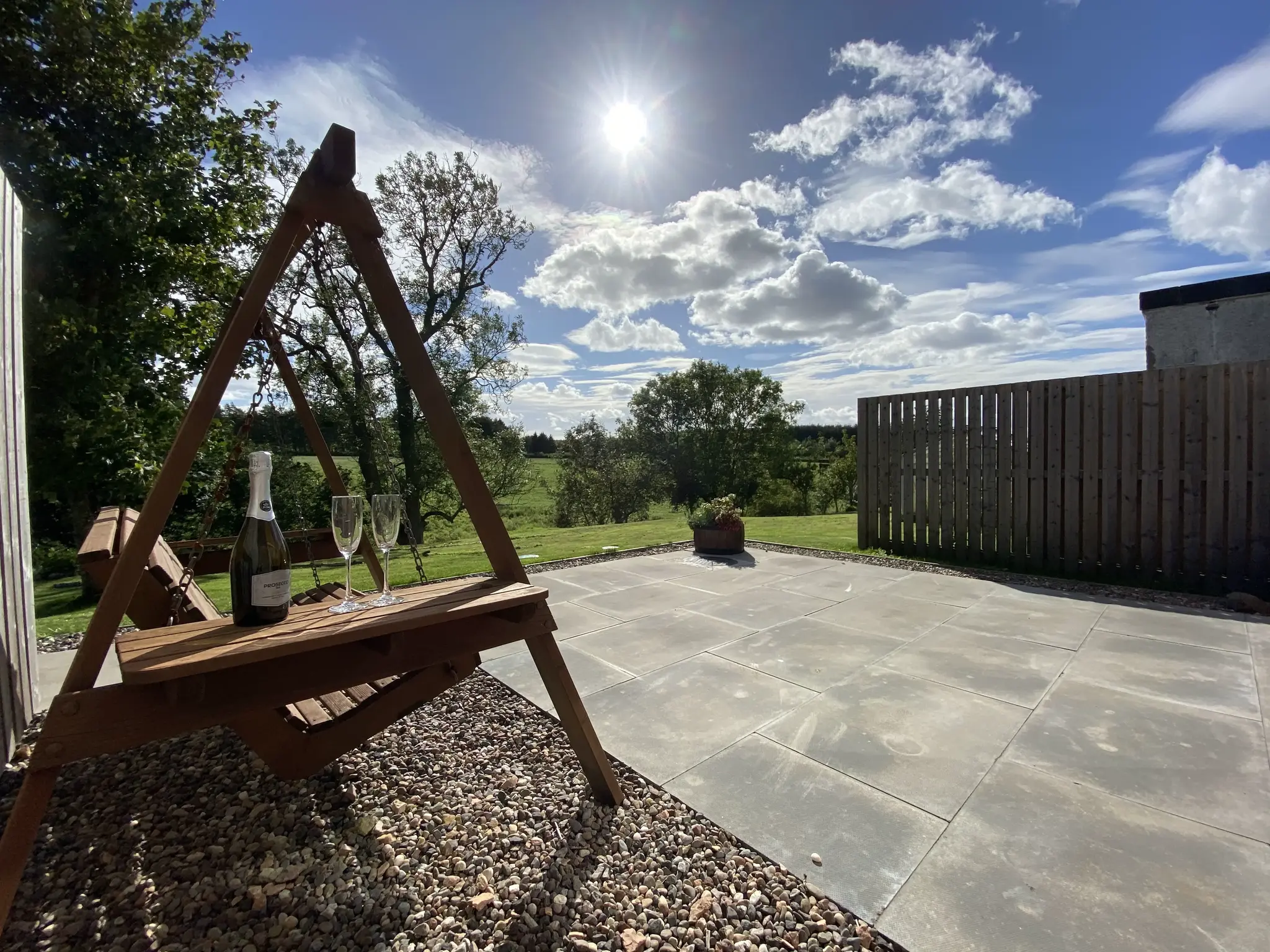 Sunny fields outside the house with a wooden swing